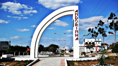 Arco branco de entrada da cidade de Andorinha, com o nome do município em vermelho, avenida urbana ao fundo e céu azul com nuvens. Foto: Divulgação/Prefeitura de Andorinha-BA