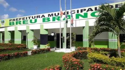 Fachada da Prefeitura Municipal de Breu Branco, prédio em tons de verde e branco, com letreiro do nome no topo, mastros com bandeiras à frente, jardim com flores e gramado bem cuidado. Foto: Divulgação/Prefeitura de Breu Branco-PA