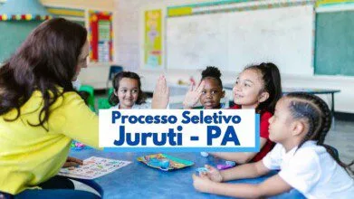 Imagem mostra uma professora interagindo com um grupo de cinco crianças pequenas em uma sala de aula colorida e bem iluminada. As crianças estão sentadas em volta de uma mesa azul, sorrindo e brincando com materiais educativos. No centro da imagem há um texto sobreposto que diz “Processo Seletivo Juruti - PA”, indicando um processo seletivo para a área da educação no município de Juruti, no Pará.