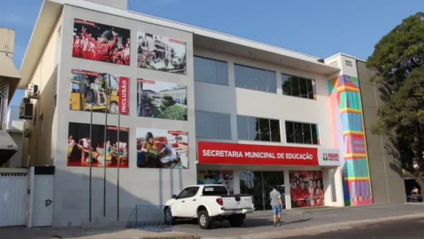 SEMED Macapá (AP) abre processo seletivo com 54 vagas imediatas 3 Fachada da Secretaria Municipal de Educação de Macapá, prédio moderno com painéis fotográficos sobre educação e inclusão, placa institucional em vermelho, veículos estacionados à frente e pessoas circulando na entrada. Foto: Divulgação/Prefeitura de Macapá