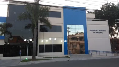 SEMED Pinheiral/RJ abre processo seletivo com 20 vagas imediatas 2 Fachada da Prefeitura Municipal de Pinheiral, prédio moderno em tons de branco, cinza e azul, com palmeira na frente e identificação institucional na parede lateral. Foto: Divulgação/Prefeitura de Pinheiral-RJ