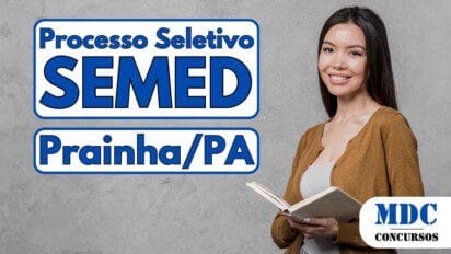 Mulher jovem de cabelos lisos e longos, sorrindo, vestindo cardigã marrom e jeans claros, segurando um caderno aberto diante de parede cinza - SEMED Prainha (PA) abre 360 vagas em Processo Seletivo na Educação