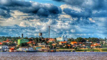 Vista panorâmica da cidade de Prainha no Pará, com destaque para construções coloridas, igreja azul e o rio em primeiro plano sob um céu com nuvens carregadas. Foto: Divulgação/Wendell Medeiros (Prefeitura de Prainha-PA)