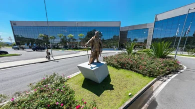 Sede da Prefeitura de Santana de Parnaíba com fachada moderna espelhada, jardins frontais e estátua em primeiro plano. Foto: Divulgação/Prefeitura de Santana de Parnaíba-SP