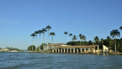 Vista de construção histórica à beira-mar em São Francisco do Conde cercada por palmeiras e céu azul claro. Foto: Divulgação/Prefeitura de São Francisco do Conde-BA