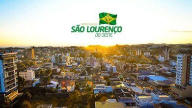 Vista aérea de São Lourenço do Oeste ao pôr do sol com prédios, casas e o logotipo da prefeitura sobreposto no céu. Foto: Divulgação/Prefeitura de São Lourenço do Oeste-SC