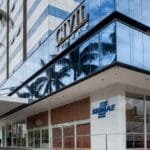 Fachada envidraçada do prédio Civil Towers com a unidade do Sebrae BA no térreo, identificada por logotipo azul na parede branca e entrada com portas de vidro.