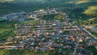 Vista aérea da cidade de Itagibá, mostrando ruas organizadas, casas com telhados avermelhados, áreas verdes e morros ao redor. Foto: Divulgação/Prefeitura de Itagibá-BA