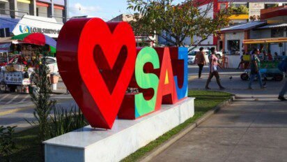 Escultura urbana com coração vermelho e as letras SAJ coloridas em Santo Antônio de Jesus-BA, com pessoas e comércios ao fundo. Foto: Divulgação/Santo Antônio de Jesus-BA