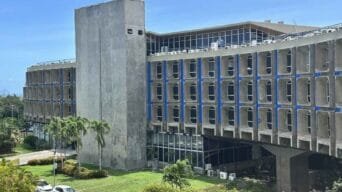 Prédio da Secretaria da Administração do Estado da Bahia com fachada de concreto, janelas emolduradas e área verde ao redor.