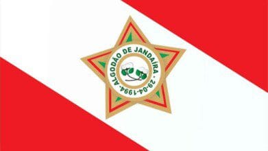 A imagem mostra a bandeira do município de Algodão de Jandaíra, na Paraíba. Ela possui um fundo com faixas diagonais vermelhas e brancas. Ao centro, há uma estrela dourada de cinco pontas com detalhes em verde e vermelho. No meio da estrela, um círculo branco contém dois ramos de algodão e a inscrição "ALGODÃO DE JANDAÍRA - 29-04-1994", que representa a data de emancipação política do município.