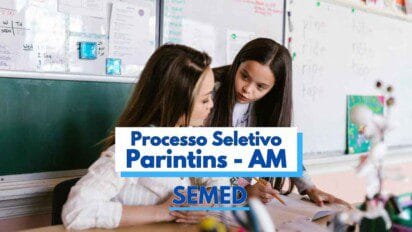 Duas mulheres estão em uma sala de aula, aparentemente uma professora e uma aluna. A professora está sentada e a aluna está de pé ao seu lado, ambas concentradas em uma atividade escrita. Ao fundo, há quadros com anotações e palavras em inglês. Sobre a imagem, há um texto informativo com os dizeres "Processo Seletivo Parintins - AM" e "SEMED".