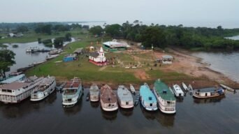 Vista aérea de Silves-AM com barcos atracados à beira do rio, igreja histórica ao centro e área com pessoas e barracas ao redor. Foto: Divulgação/Prefeitura de Silves-AM