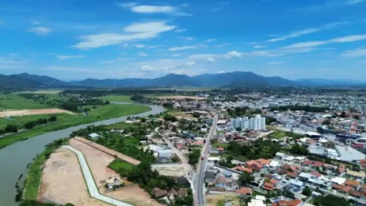 Vista aérea da cidade de Tijucas em Santa Catarina com rio, áreas urbanas e montanhas ao fundo. Foto: Divulgação/Prefeitura de Tijucas-SC