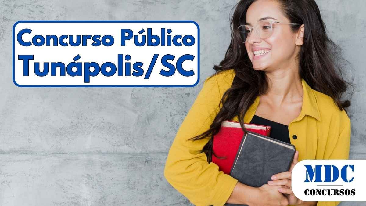 Tunápolis (SC) oferece remuneração de até R$ 5,1 mil em Concurso Público 1 Mulher sorridente com óculos transparentes, usando camisa amarela e segurando dois livros, um vermelho e um preto, em frente a uma parede cinza - Tunápolis (SC) oferece remuneração de até R$ 5,1 mil em Concurso Público