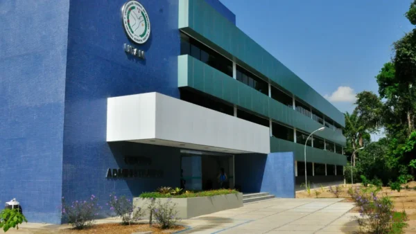 Fachada do centro administrativo da UFAM em tons de azul e verde, exibindo o brasão da universidade em destaque na parede lateral. Foto: Divulgação/UFAM