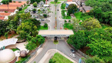 Processos Seletivos 4 Vista aérea da entrada principal da Universidade Federal da Bahia - UFBA, com portaria, árvores ao redor e área de estacionamento ao fundo.