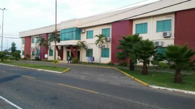 Prédio administrativo da Universidade Federal de Roraima com fachada em tons claros e vermelho, janelas verdes, palmeiras na frente e acesso pela via interna do campus. Foto: Divulgação/Google Maps (Micky Brian)