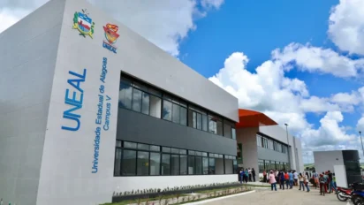 Fachada de prédio moderno da UNEAL Campus V, com letreiros azul e branco e brasão da universidade, sob céu azul com nuvens, em referência ao Concurso UNEAL 2026