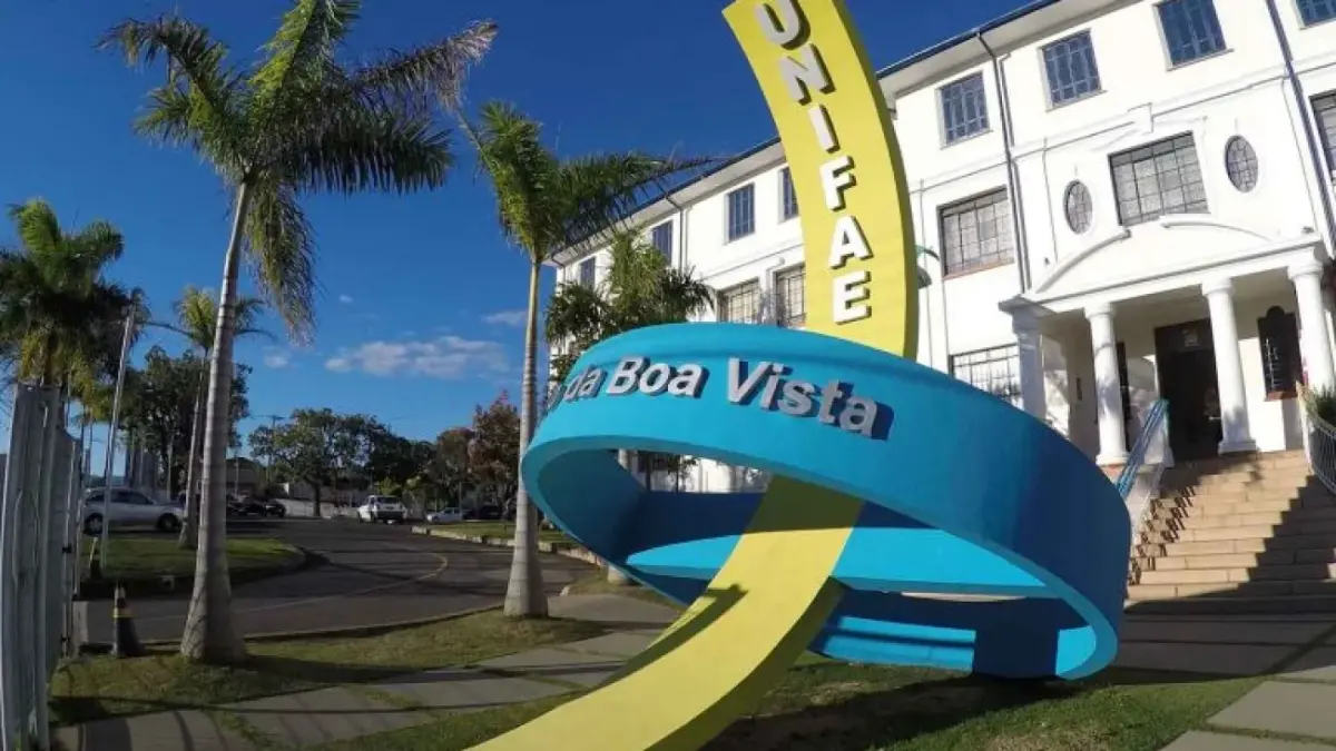 Fachada do Centro Universitário UNIFAE em São João da Boa Vista, destacando monumento colorido com o nome da instituição e palmeiras ao redor.