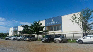 Fachada do UNITINS Câmpus Graciosa com estacionamento em frente e vários carros estacionados sob céu azul com poucas nuvens.