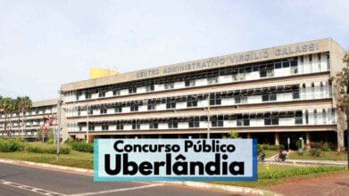 A imagem mostra a fachada do Centro Administrativo Virgílio Galassi, sede da Prefeitura de Uberlândia, Minas Gerais. O prédio é amplo, com vários andares, janelas espelhadas e estrutura de concreto. Em primeiro plano, há uma avenida asfaltada e áreas verdes com plantas ornamentais. Na parte inferior da imagem, há uma faixa com os dizeres "Concurso Público Uberlândia" em destaque.