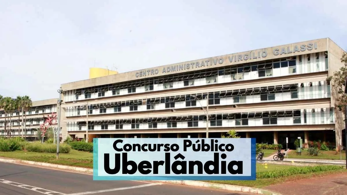 Uberlândia abre concurso com 172 vagas de até R$ 10,5 mil 1 A imagem mostra a fachada do Centro Administrativo Virgílio Galassi, sede da Prefeitura de Uberlândia, Minas Gerais. O prédio é amplo, com vários andares, janelas espelhadas e estrutura de concreto. Em primeiro plano, há uma avenida asfaltada e áreas verdes com plantas ornamentais. Na parte inferior da imagem, há uma faixa com os dizeres "Concurso Público Uberlândia" em destaque.