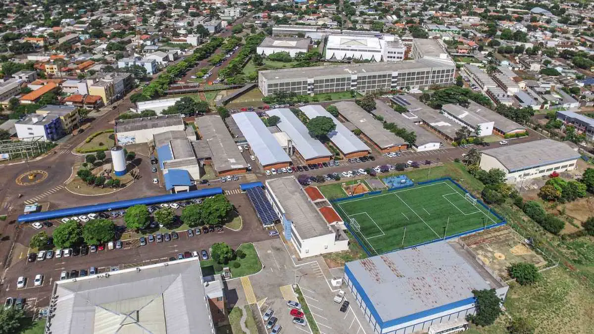 Especialização Gratuita EaD na Unioeste oferece 420 vagas 4 Vista aérea de um campus universitário da Unioeste Cascavel com prédios, estacionamentos, área verde e um campo de futebol cercado por rede. Foto: Divulgação/Unioeste