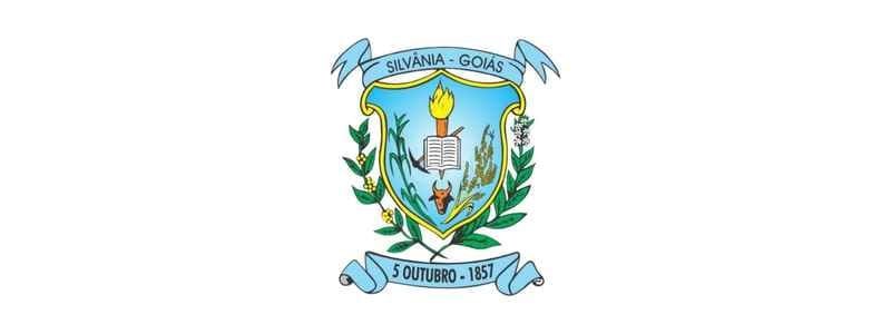Silvânia GO abre processo seletivo c/ 563 vagas de até R$ 4,8 mil 1 Imagem do brasão oficial do município de Silvânia, em Goiás. No centro do escudo azul, há uma tocha acesa sobre um livro aberto, representando o conhecimento e a educação. Abaixo, aparece uma figura humana com os braços erguidos, cercada por ramos de milho e flores. O escudo é contornado por folhas verdes e faixas azuis com os dizeres "Silvânia – Goiás" na parte superior e "5 Outubro – 1857" na parte inferior, referindo-se à data de fundação do município.