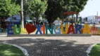 Letreiro turístico colorido com a frase "Eu amo Xinguara", onde a palavra "amo" é substituída por um coração vermelho, localizado em uma praça arborizada com parquinho infantil ao fundo.